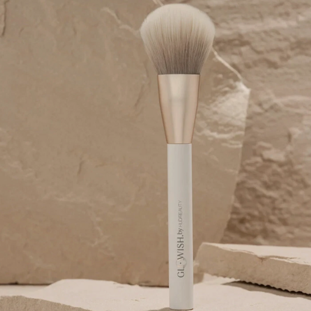 huda beauty glowish all over bronzer brush on rocky background