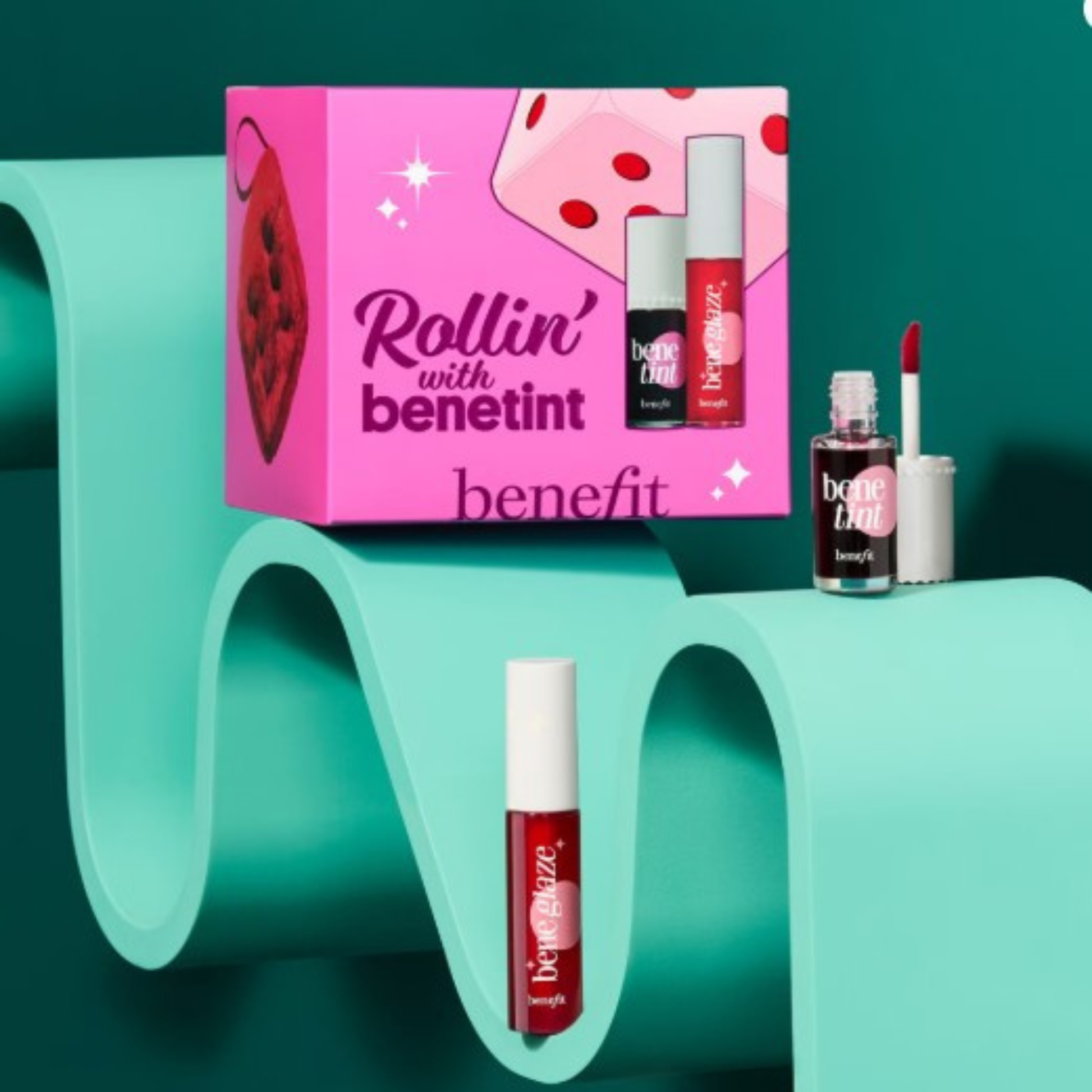 Benefit lip product set with pink packaging on a teal background